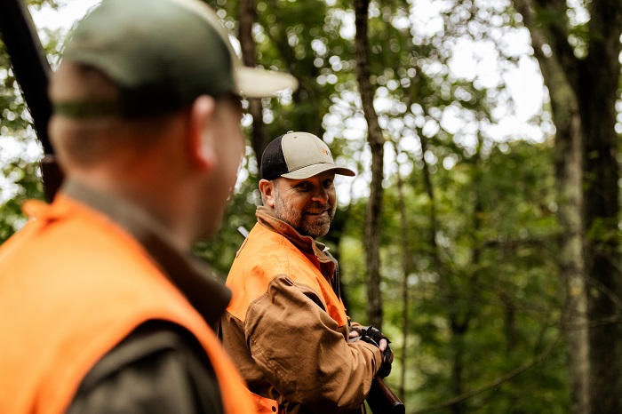 Two hunters have a conversation in the woods