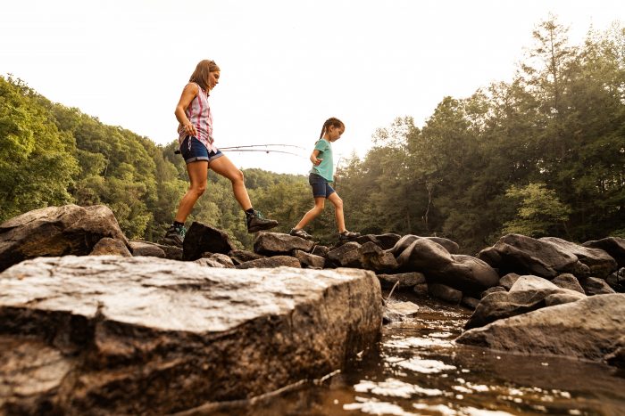 A mother and daughter hop rocks on their way to go fishing