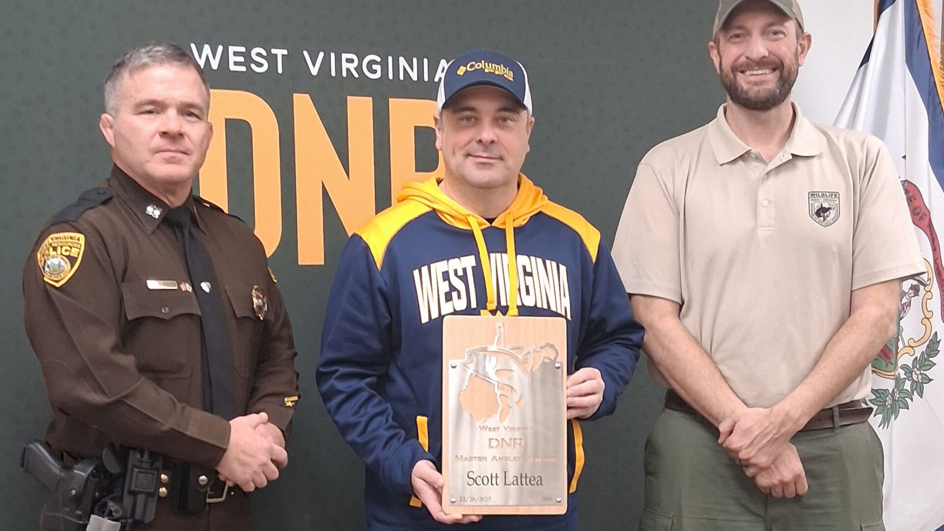 Man accepts Master Angler award from uniformed WVDNR Natural Police Officer and Fisheries Biologist.