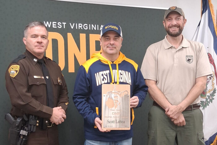 Man accepts Master Angler award from uniformed WVDNR Natural Police Officer and Fisheries Biologist.